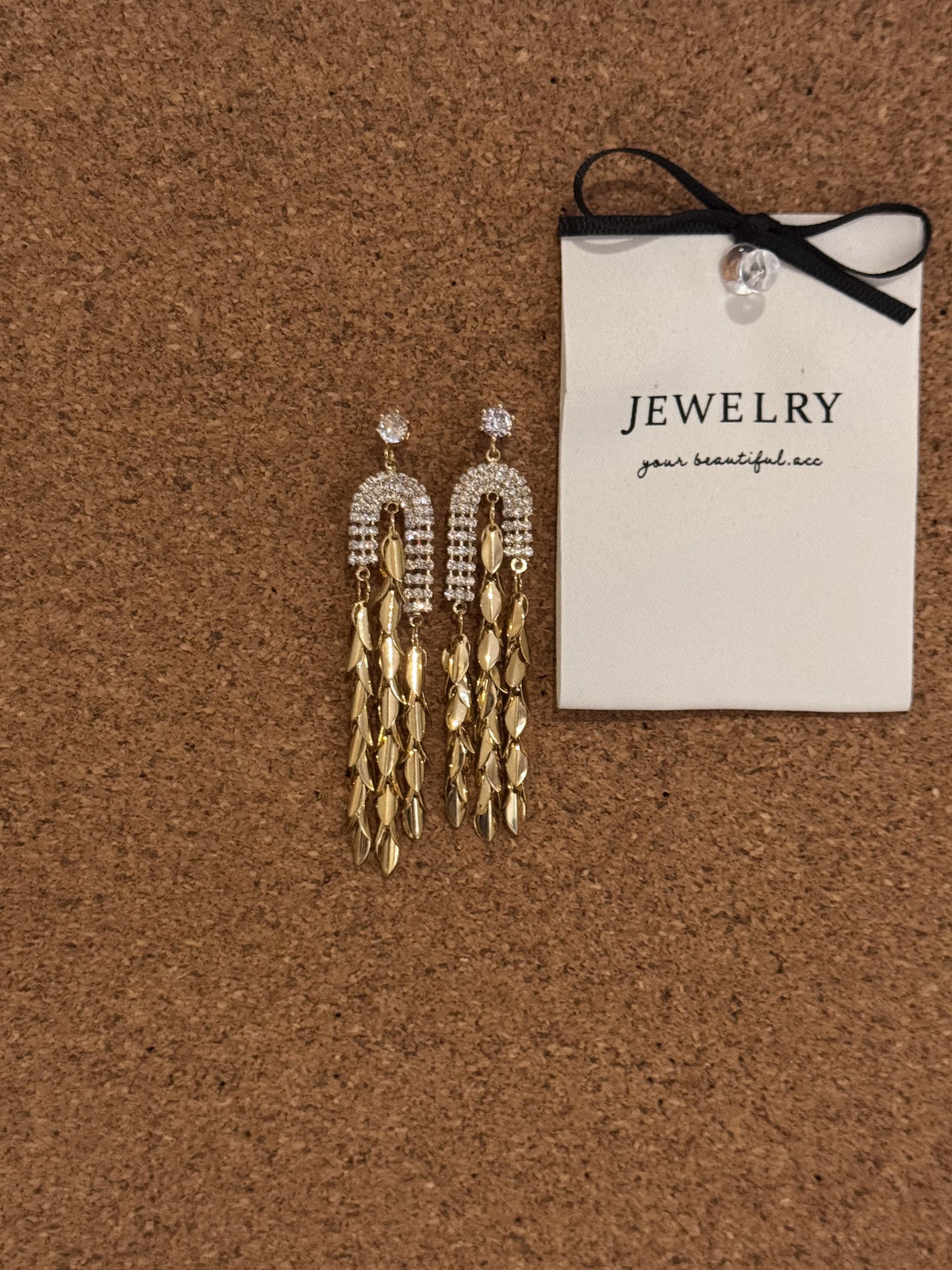 Gold-tone dangle earrings with crystal accents and leaf-shaped tassels.