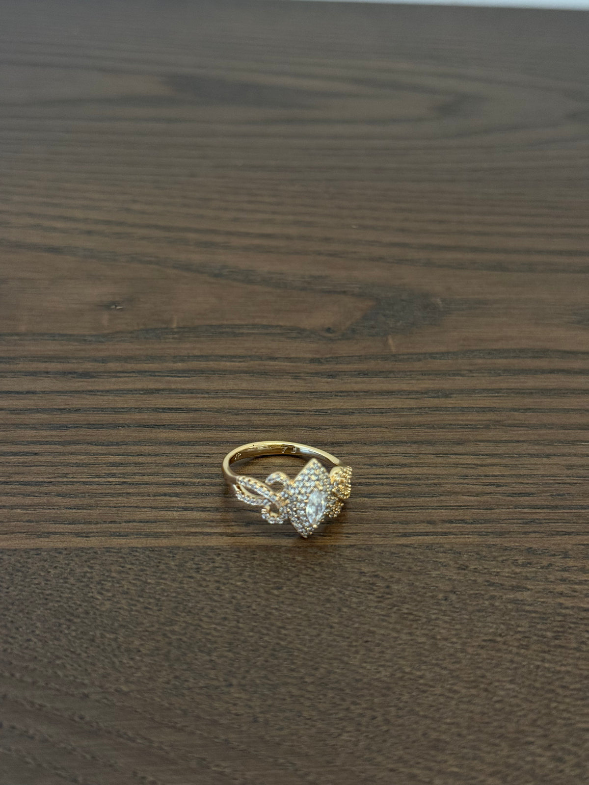 Gold-tone butterfly ring with clear rhinestones on wood surface
