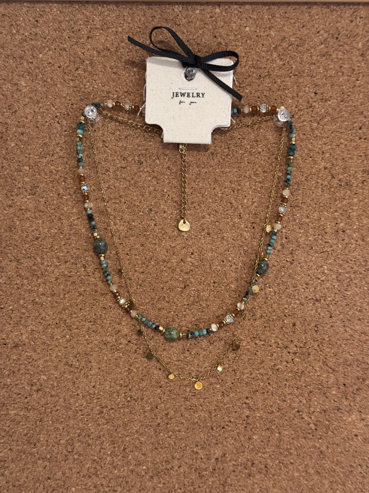 A layered necklace with blue stone beads and gold-tone chain charms.