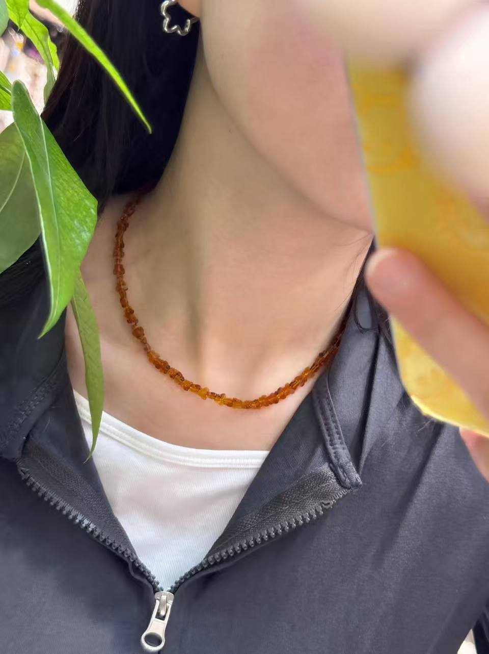 Amber-colored beaded necklace worn on the neck, minimalist fashion jewelry with small translucent beads