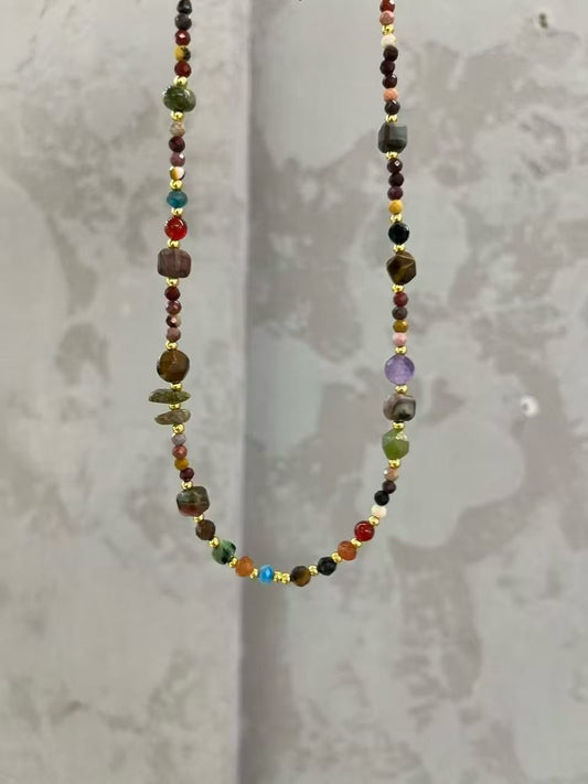 Colorful gemstone beaded necklace with gold spacers on a neutral background