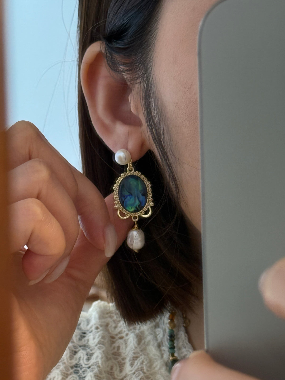 Gold-tone drop earring with oval blue-green iridescent stone, pearl stud, and pearl drop